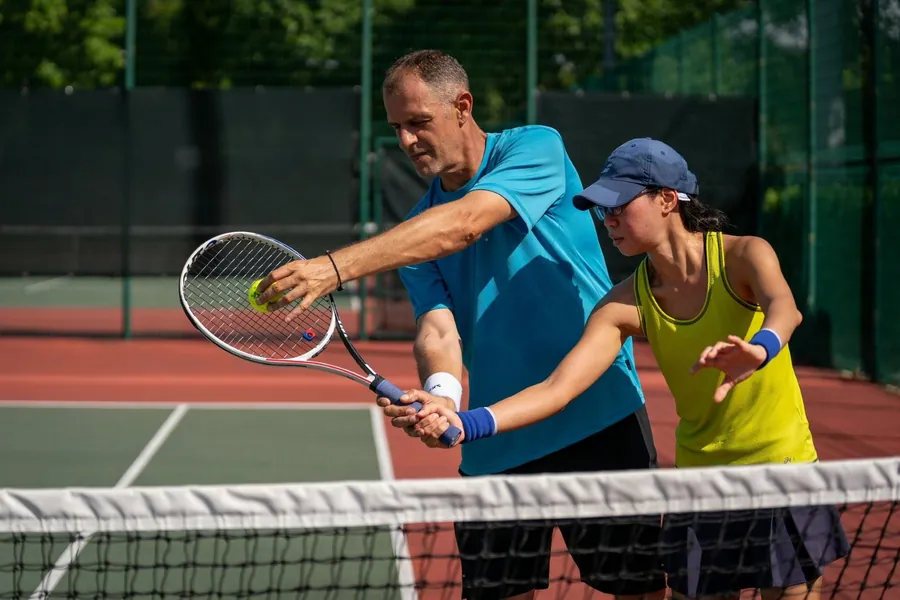 Coach Fred guiding a student's forehand at the net